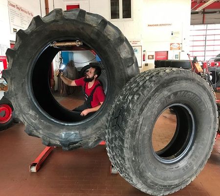 Großreifenreparatur mit einem Mitarbeiter in Arbeitskleidung in der Werkstatt