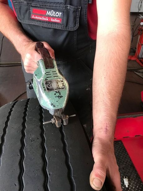 Ein Mitarbeiter bearbeitet einen Reifen mit einer Maschine