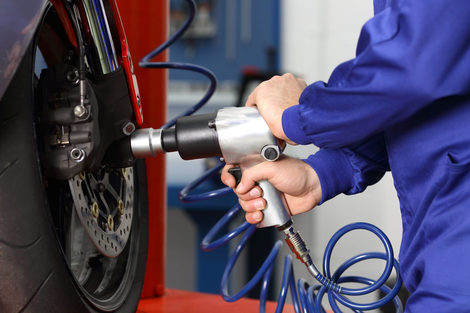 Eine Hand demontiert einen Motorradreifen mit einer Maschine